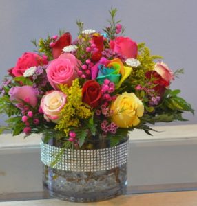 yellow pink and red roses with greenery and vase