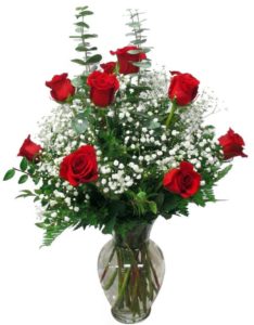 A CLASSIC DOZEN red ROSES ARRANGED IN A VASE WITH ASSORTED GREENS AND FILLERS.