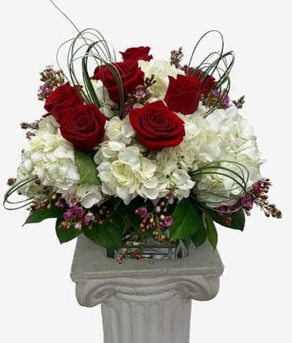 Beautiful red roses with white hydrangea and greenery in a lush bountiful displat