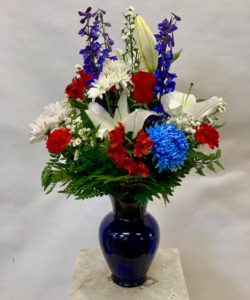 Large colbolt blue vase with mixed red, white and blue flowers