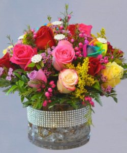 A beautiful assortment of different color roses tucked into a gem studded vase and with added gem stones