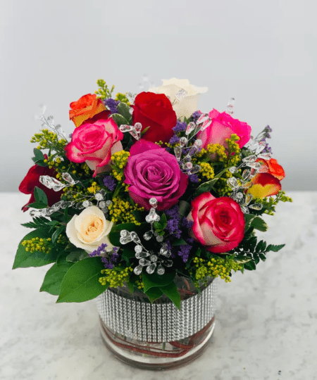 A beautiful assortment of different color roses tucked into a gem studded vase and with added gem stones for that special someone.